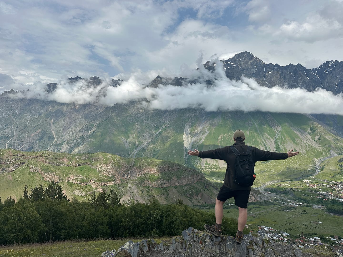 View of the Caucasus Mountains in Kazbegi, Georgia, with Mount Kazbek hidden behind clouds.