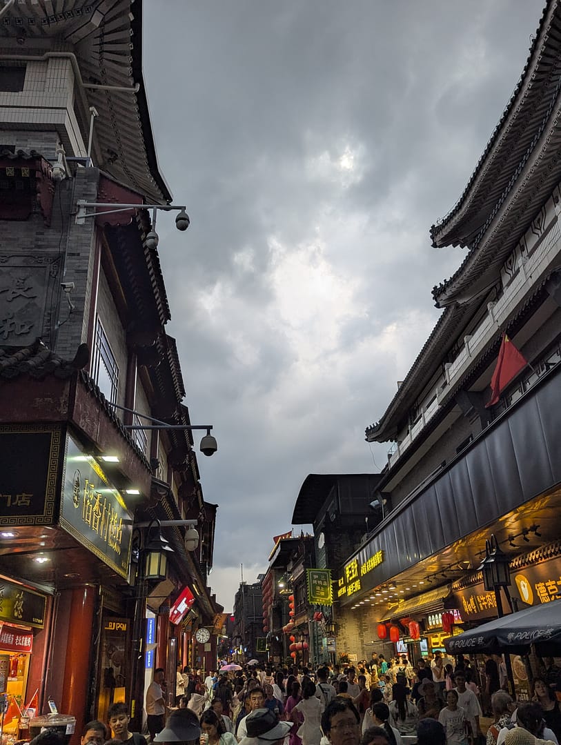 Dashilan Street in Beijing at night, crowded with people and lit by shop lights.