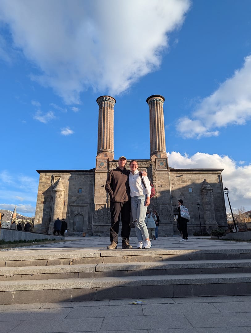 Sarah and Callum standing in front of a mosque in Erzurum, Turkey, during their overland trip